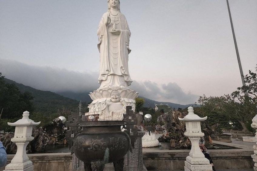 A large white statue of a figure with a lotus base, surrounded by smaller statues and architectural elements. 5