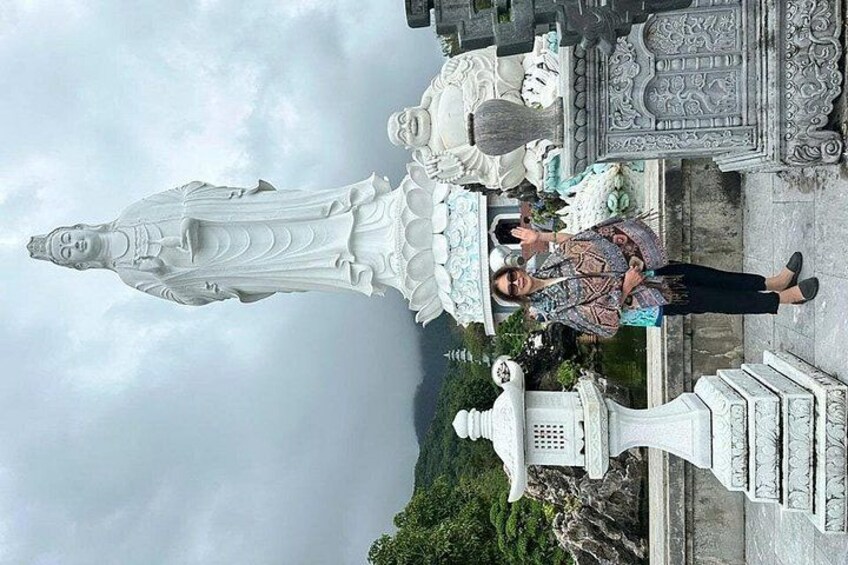A person standing in front of a large white statue, with a mountainous landscape in the background. 3
