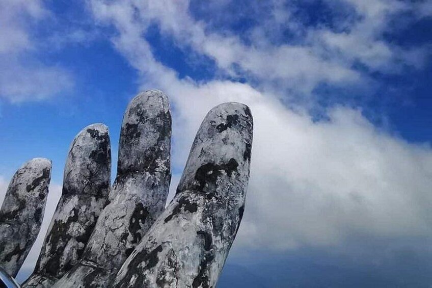 En skulptur i form av en hand med en molnig himmel i bakgrunden. 3