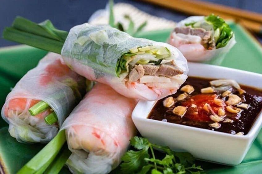 A plate of Vietnamese spring rolls with a side of dipping sauce. 2