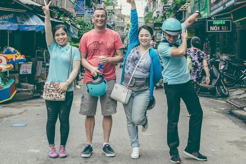 Four people walking on a street, one holding a helmet, another with a water bottle, and a third with a backpack. 4
