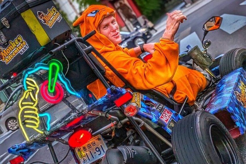 A person in an orange costume riding a motorcycle with neon lights and a monkey figure. 2