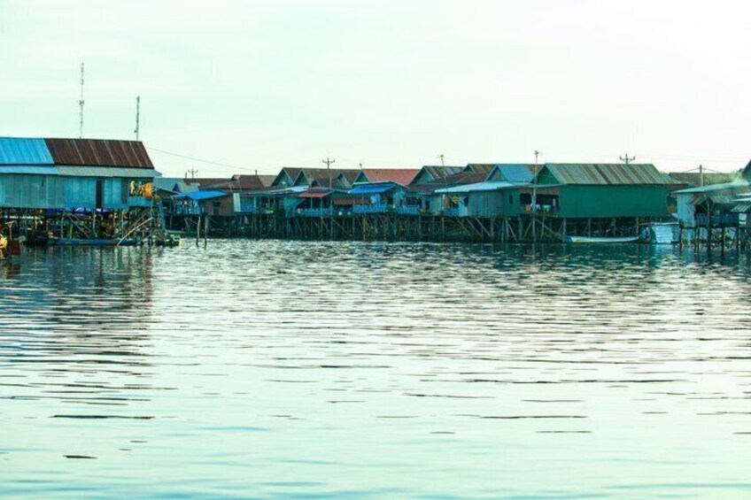 A waterfront with stilt houses and a calm river. 1