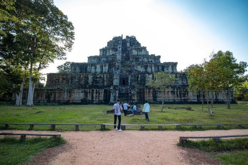 A large ancient temple complex with visitors standing in the foreground. 1