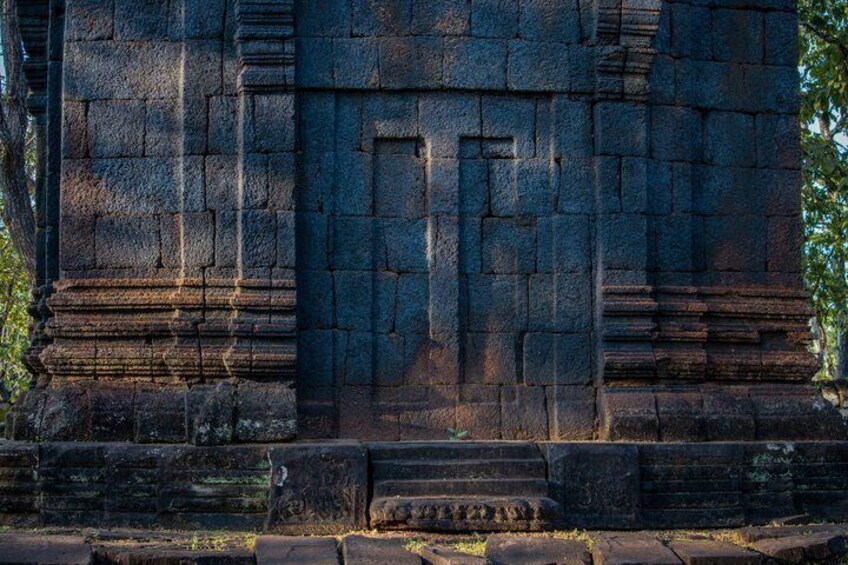A stone temple with a central doorway and steps leading up to it. 4