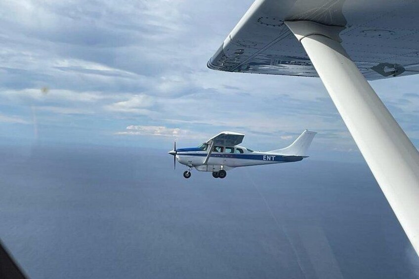 A small airplane flying over a vast body of water with a clear sky. 5