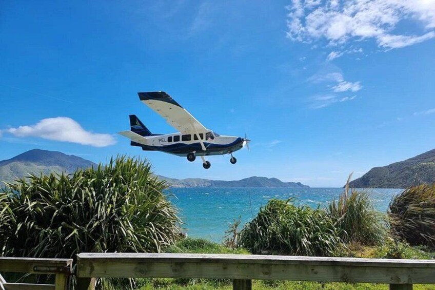A small airplane flying over a coastal landscape with mountains in the background. 2