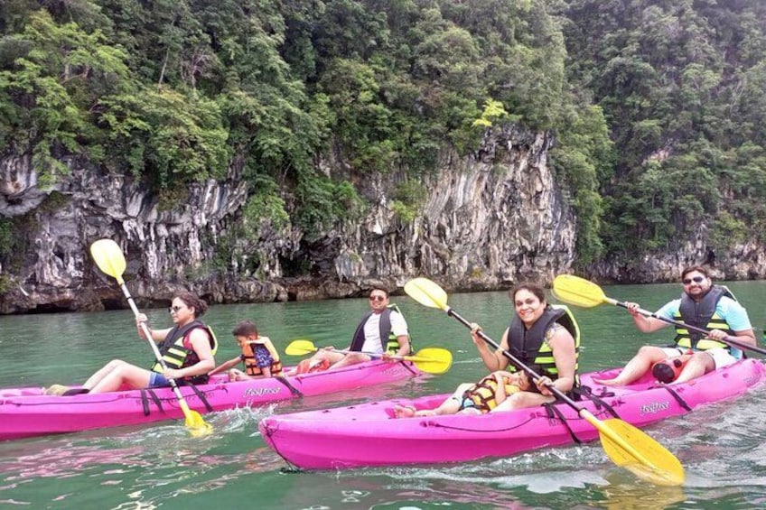 People kayaking on a river with a rocky cliff in the background. 4