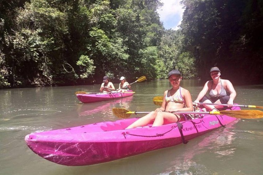 Two people kayaking on a river surrounded by dense greenery. 5