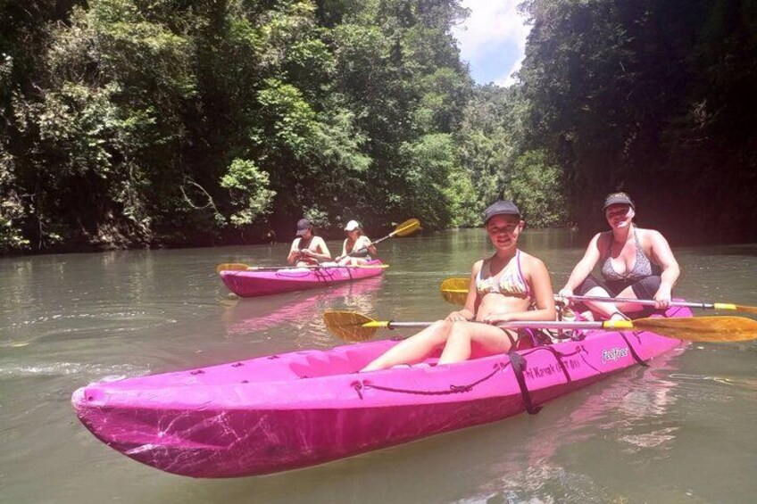Two people kayaking on a river surrounded by dense greenery. 5