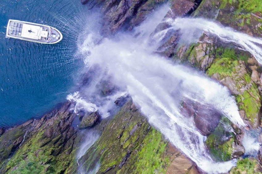 A boat on a calm sea, a waterfall, and rocky terrain. 3