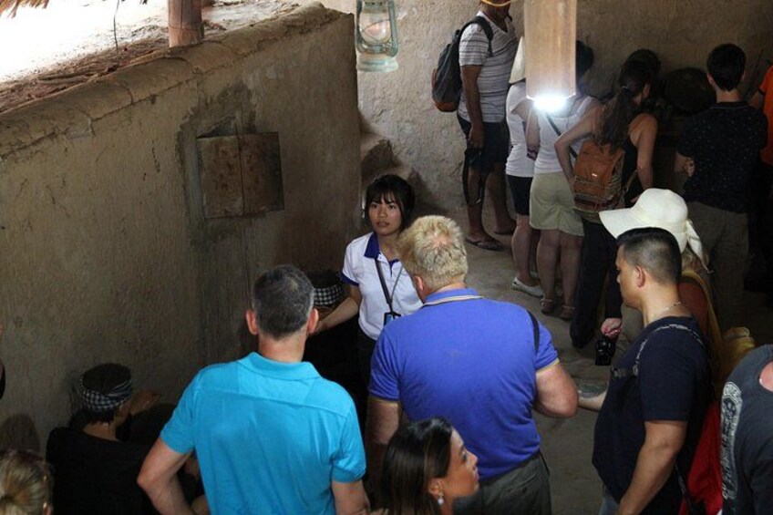 A group of people in a narrow, dimly lit corridor with rough walls and a rustic ceiling. 4
