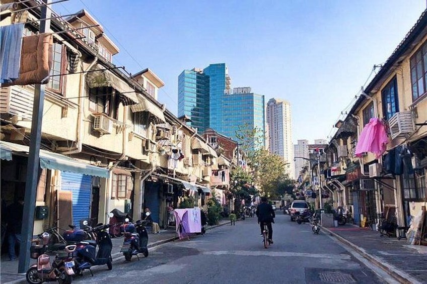 A narrow street lined with traditional buildings, a cyclist, and parked motorcycles. 3