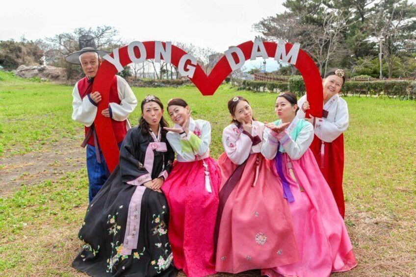 En gruppe mennesker i traditionelt koreansk tøj poserer foran et banner med teksten 'YONGDAM'. 3