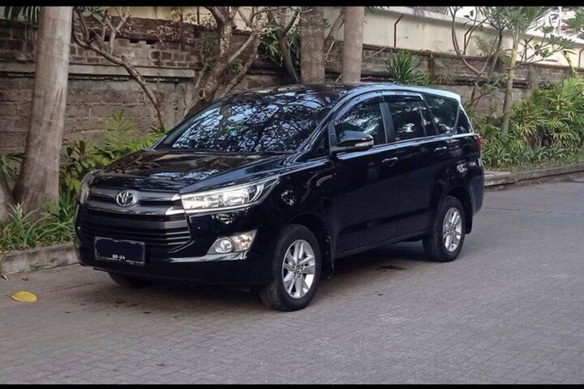 Een zwarte Toyota SUV geparkeerd op een verharde weg, met een stenen muur en groen in de achtergrond. 2