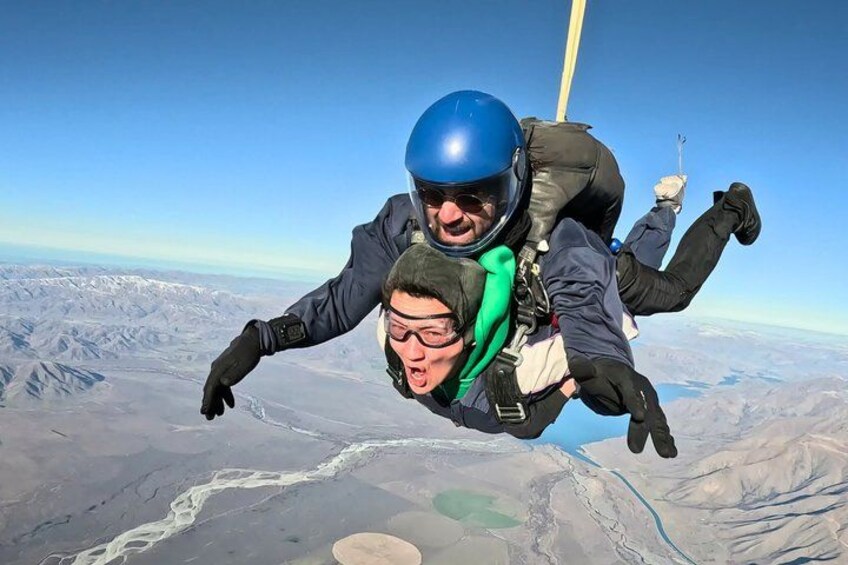 Two people skydiving with a mountainous landscape below. 5
