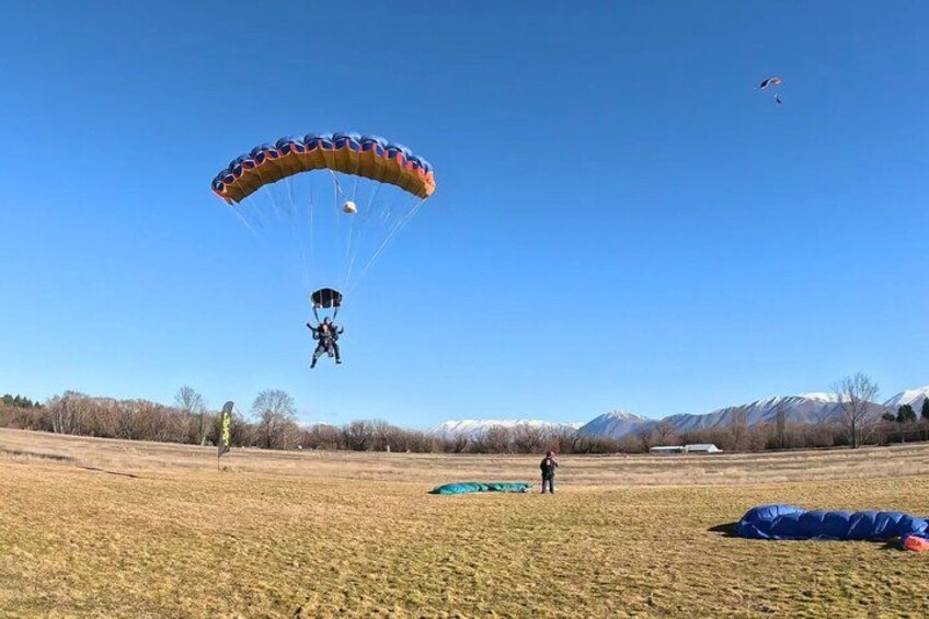 A person parachuting in a field with mountains in the background. 2