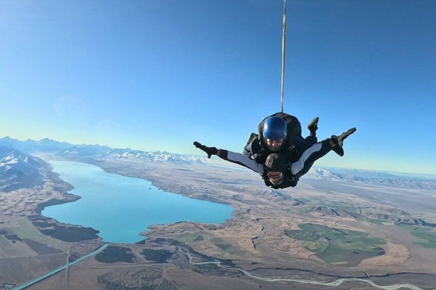 A person skydiving with a parachute over a landscape with mountains and a lake. 5