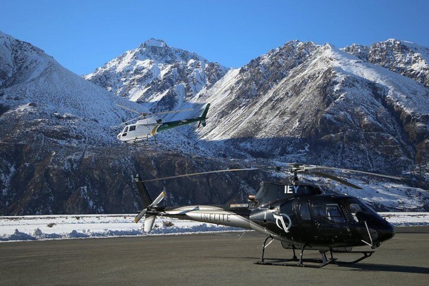 Ein Hubschrauber auf einer Startbahn, im Hintergrund verschneite Berge. 3