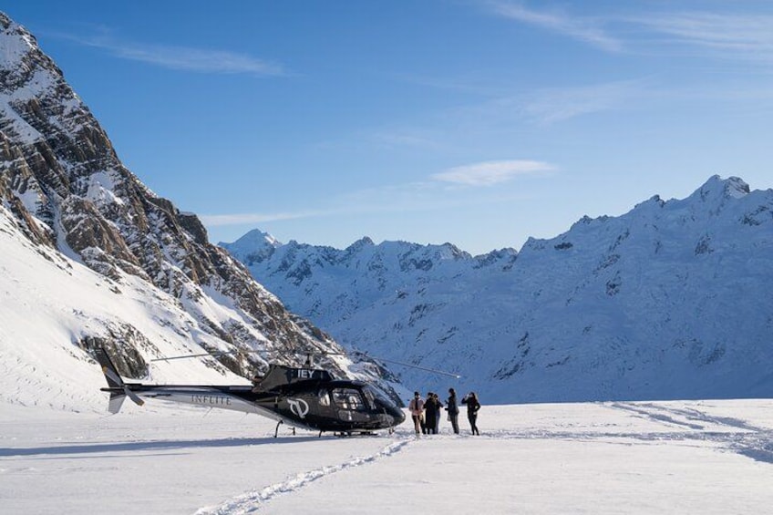 A helicopter on a snowy mountain with people standing nearby. 5