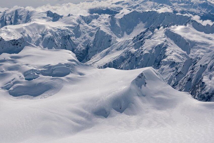 A snow-covered mountain range with rugged peaks and deep valleys. 4