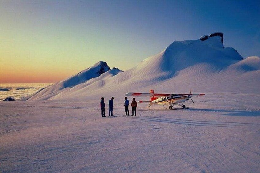 A snowy landscape with a small airplane and people standing on the snow. 5