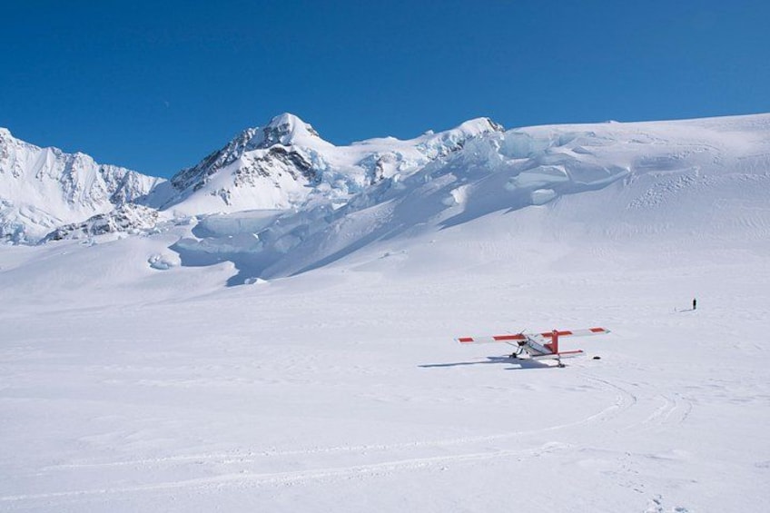 A snow-covered landscape with a red and white aircraft on the ground. 4
