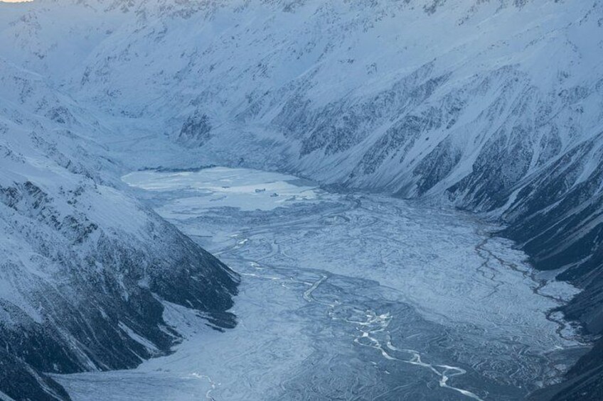 A glacier with a crevasse and snow-covered mountains. 3
