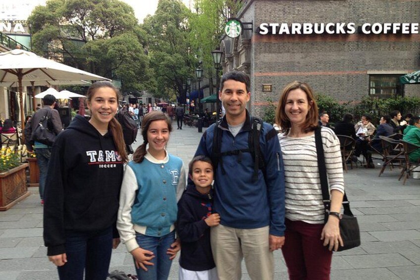 A family of five posing in front of a Starbucks Coffee sign. 1