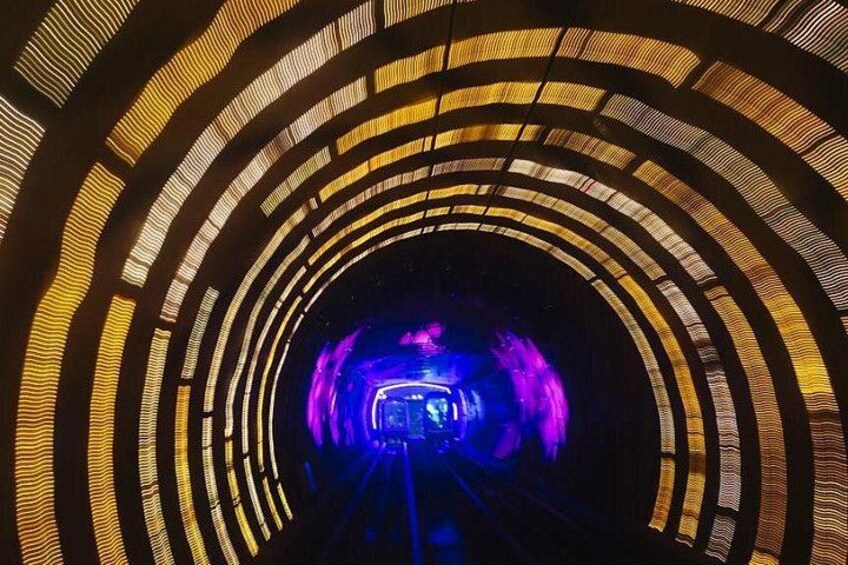 A tunnel with circular patterns and a blue light at the end. 3