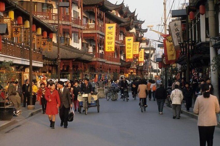 A bustling street with traditional architecture, people walking, and bicycles. 4