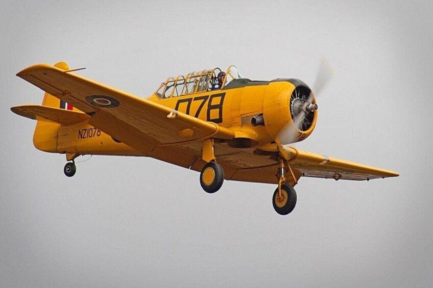 A yellow biplane with the number 078 flying. 1