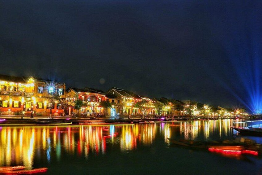 A nighttime riverside scene with illuminated buildings reflecting on the water. 2