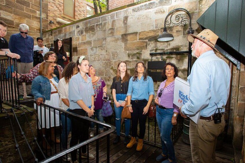 A group of people standing on a wooden staircase in a building with stone walls. 1