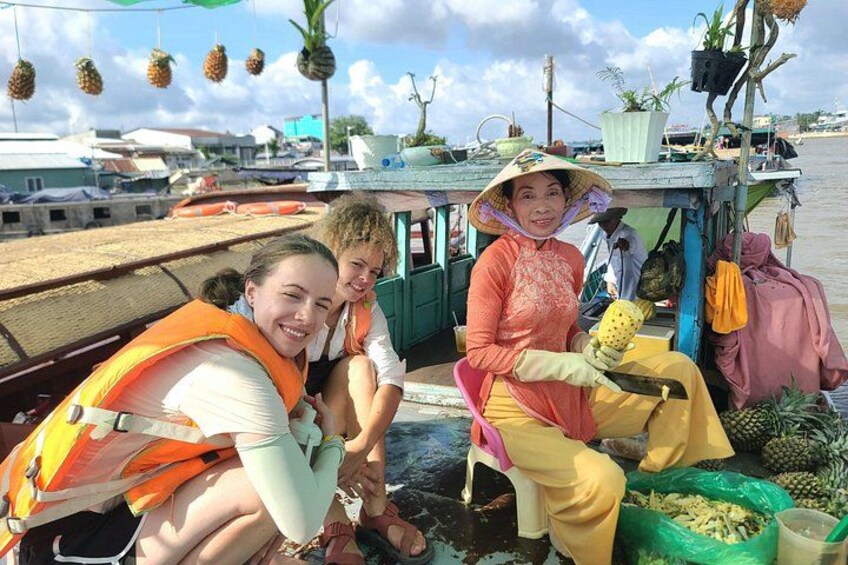 A boat with people wearing life jackets, a woman in a hat, and pineapples on the deck. 5