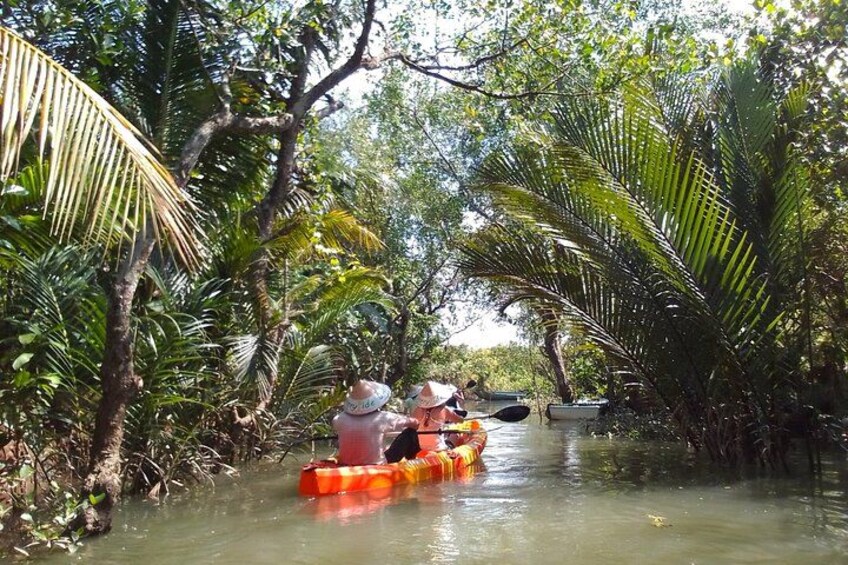 Two people in a canoe on a narrow waterway surrounded by dense tropical vegetation. 2