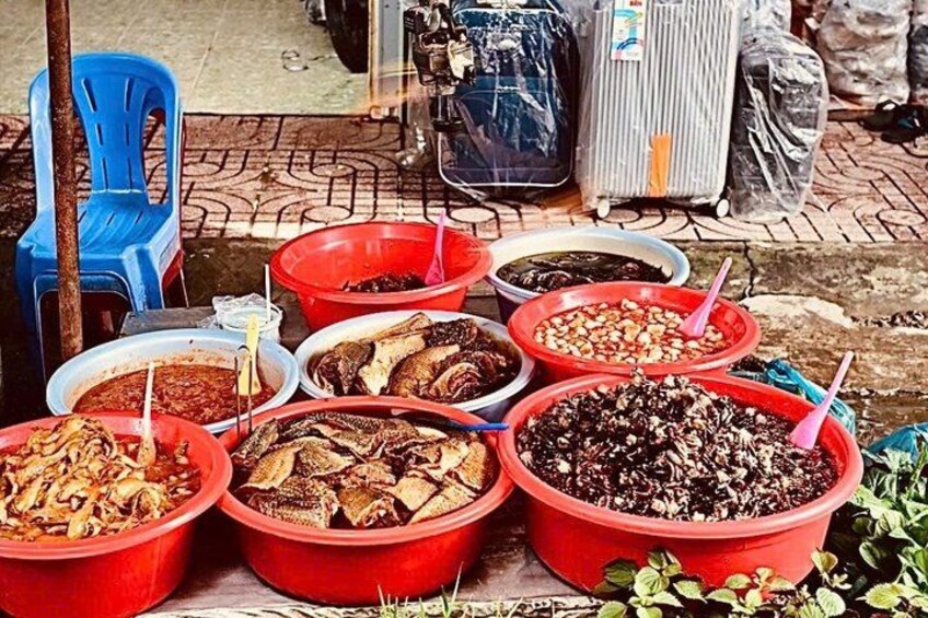 Une variété d’aliments servis dans des bols rouges accompagnés de cuillères, le tout disposé sur une table à l’extérieur. 4