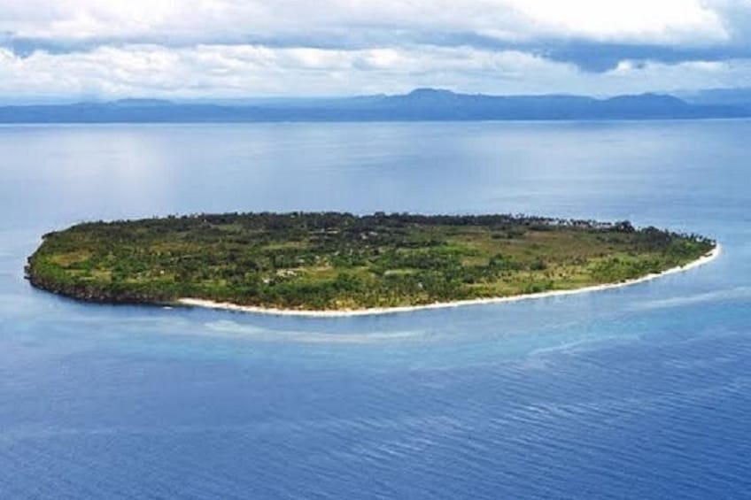 An island surrounded by calm blue waters, with a clear sky above. 1
