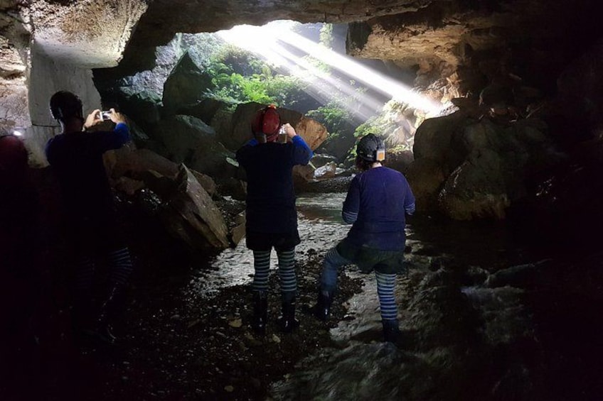 Menschen erkunden eine Höhle mit Wasser und Felsen. 4