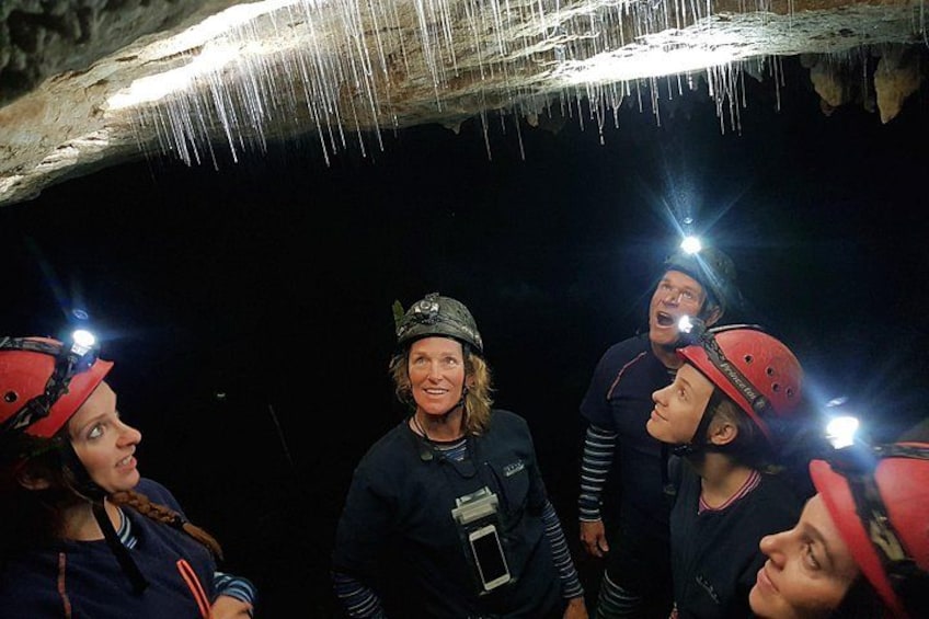 A group of people in a cave with helmets and headlamps. 4