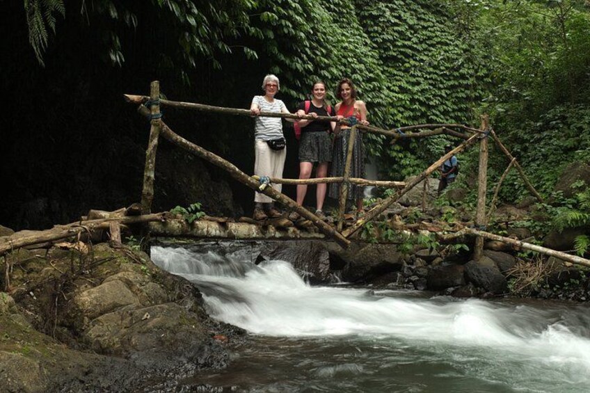 A wooden bridge over a flowing river in a forested area. 3