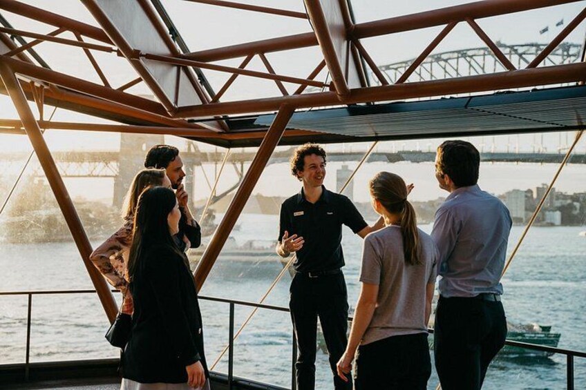 Een groep mensen staat op een boot, met een brug op de achtergrond. 2