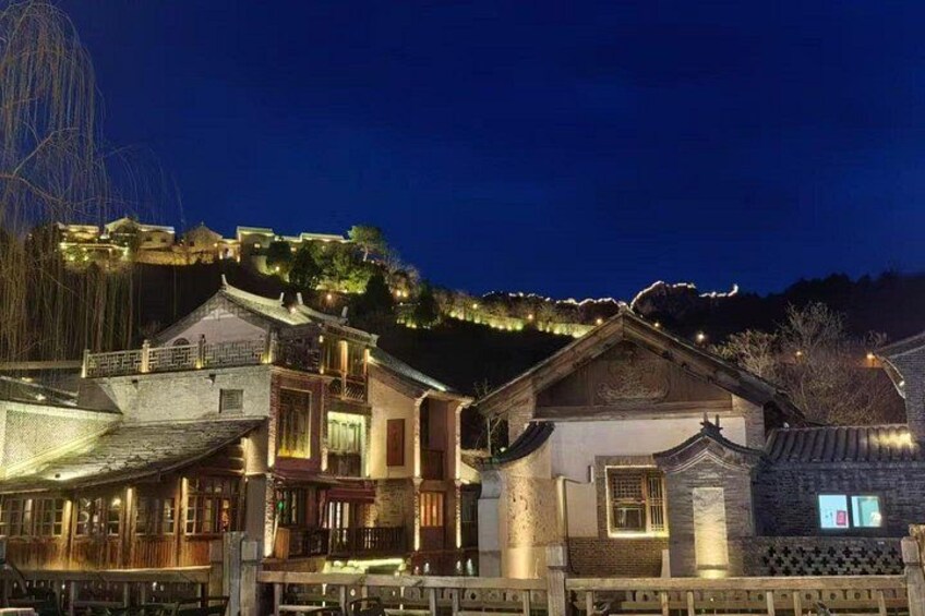 Traditional buildings with illuminated rooftops and a hill in the background. 3