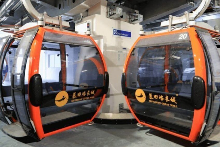 Two orange and black cable cars with 'MUTIANYU GREAT WALL' written on them. 1