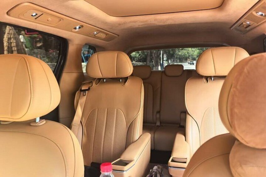 A car interior with tan leather seats and a sunroof. 3