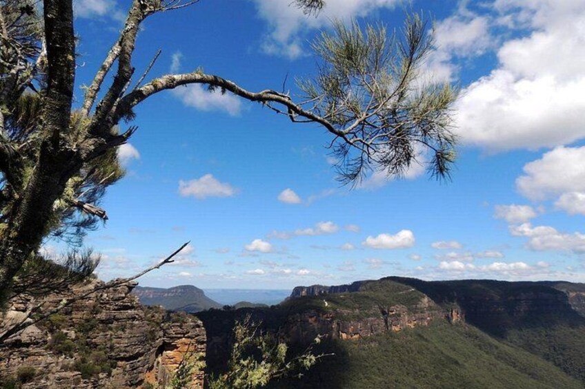 A mountainous landscape with a clear sky, rocky terrain, and sparse vegetation. 3