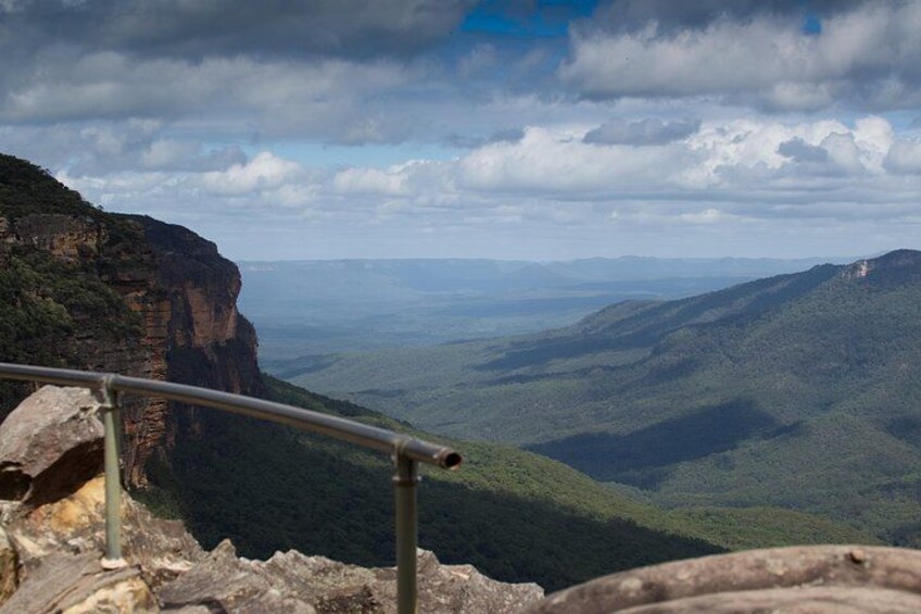 A mountainous landscape with a railing, cliffs, and a distant view of the horizon. 2