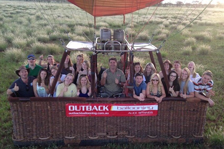 A group of people in a wicker hot air balloon with a sign that reads 'OUTBACK ballooning.' 3