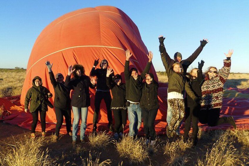 A group of people standing in front of a large red hot air balloon. 5
