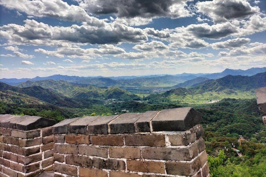 A brick wall of the Great Wall of China with a mountainous landscape in the background. 2